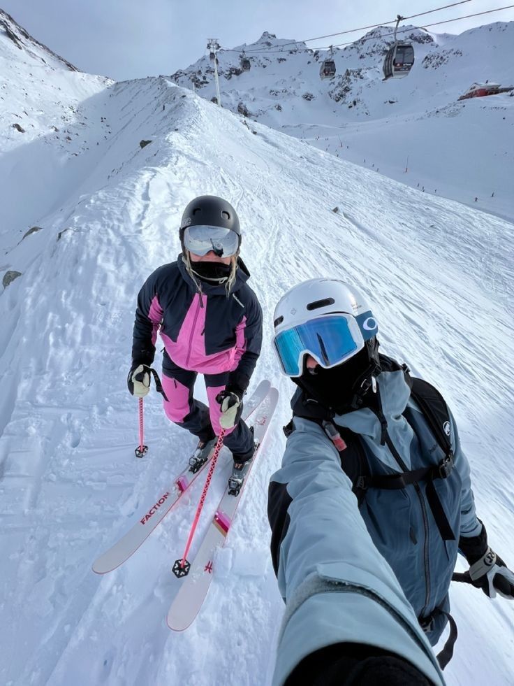 two people on skis standing in the snow