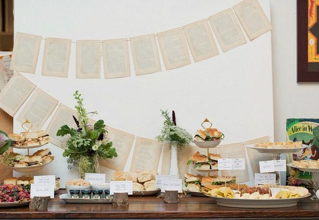 a table topped with lots of food next to a book page banner on the wall