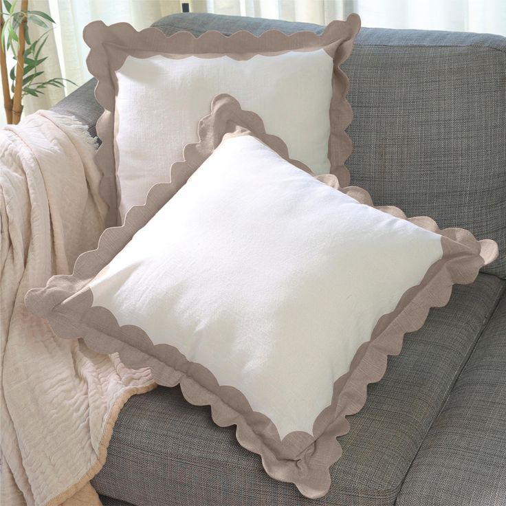 two white pillows on a gray couch