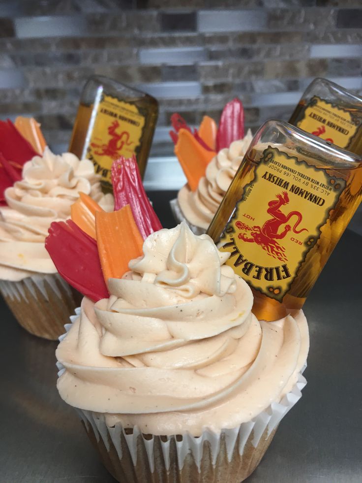 cupcakes with white frosting and candy sticks on top are sitting on a table