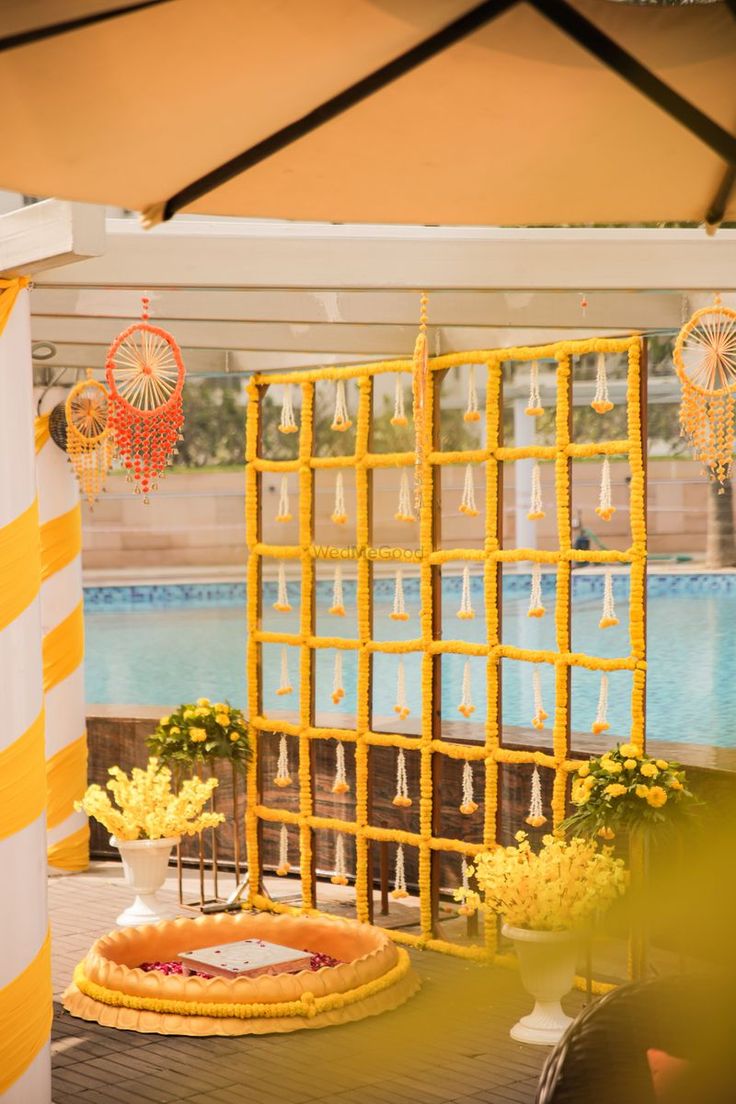 an outdoor area with yellow and white decorations next to a swimming pool in the background