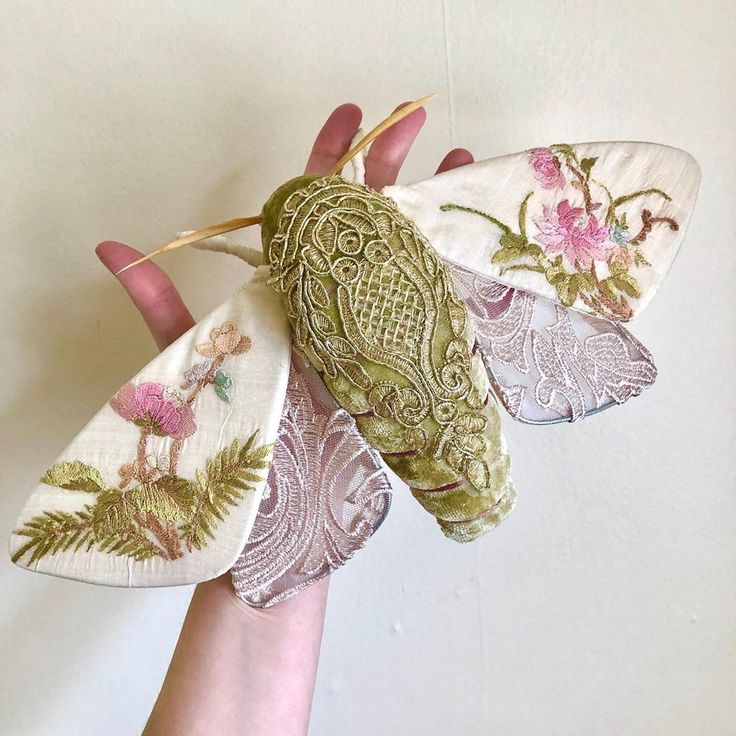 a person's hand holding three fabric butterflies