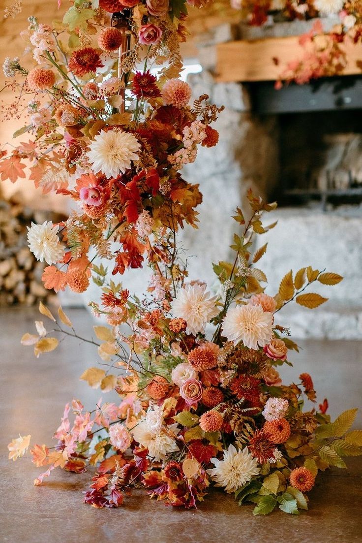 an arrangement of flowers on the floor in front of a fireplace