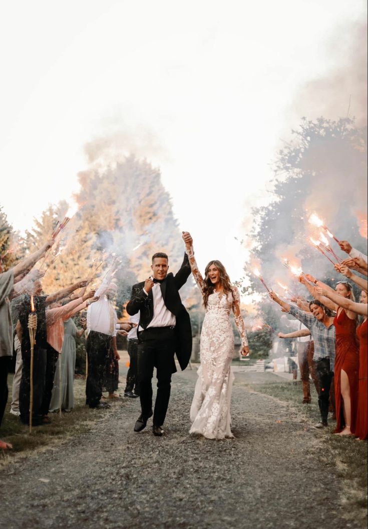 a newly married couple walking down the road with their arms in the air as confetti is thrown around them