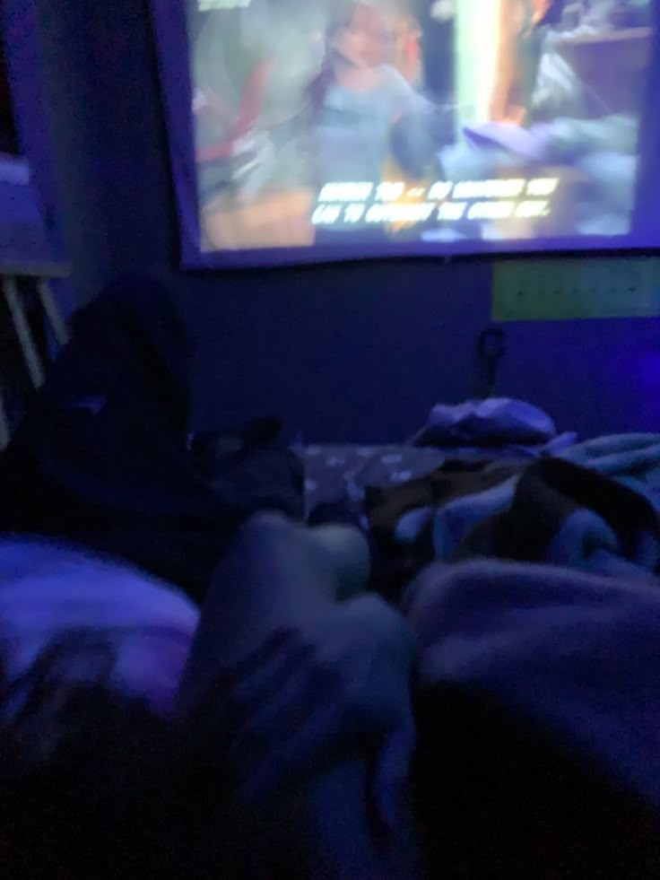 a person laying in bed and watching tv