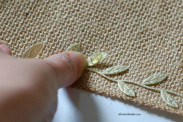 someone is stitching together some fabric with gold leaf appliques on it's side