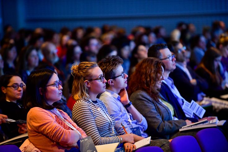 many people are sitting in rows and listening to the speaker at the conference or seminar