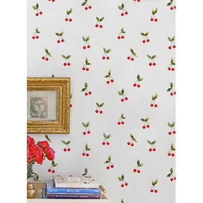 the wall paper has cherries on it and is next to a vase with flowers