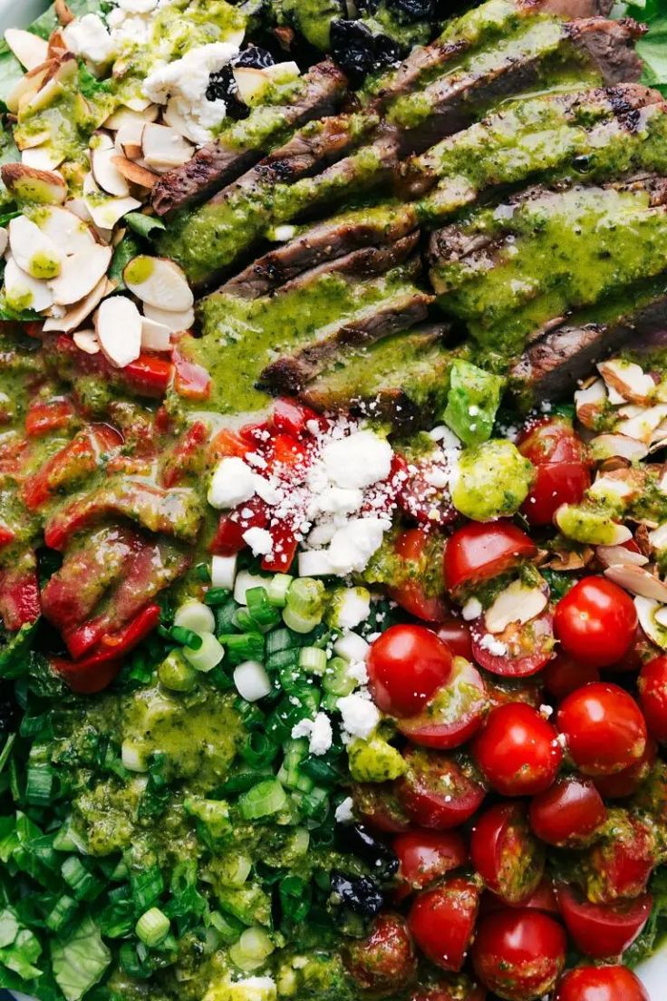 a white plate topped with meat and veggies covered in pesto, tomato sauce