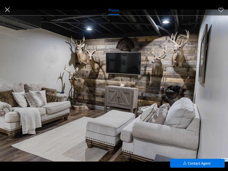 a living room with deer heads on the wall and couches in front of it