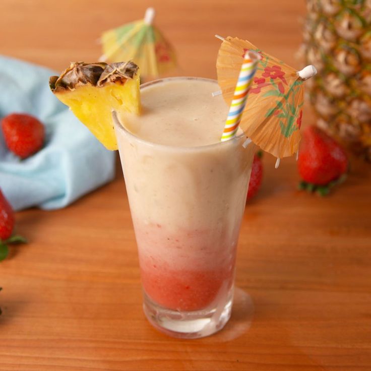 there is a drink on the table with strawberries and umbrellas in the background