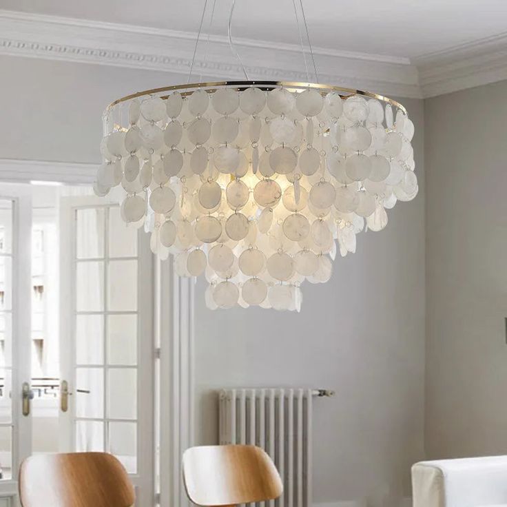 a chandelier hanging from the ceiling in a room with white walls and chairs