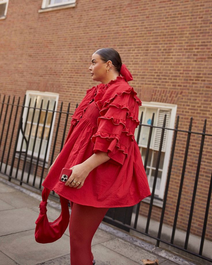 a woman in red is walking down the street