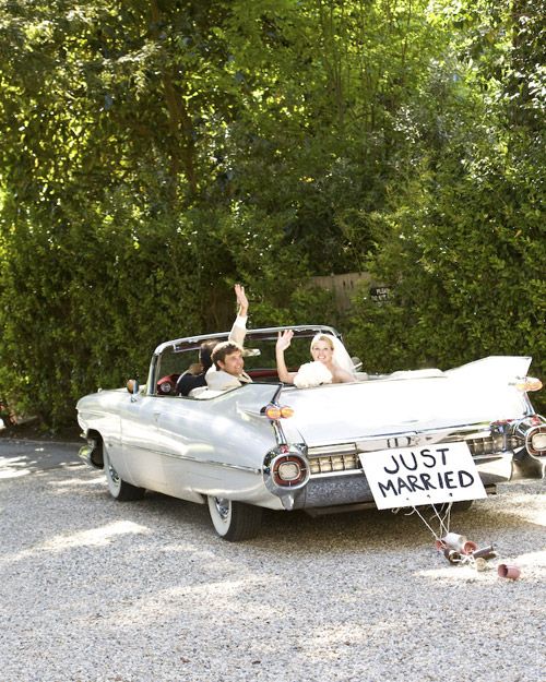 two people in an old fashioned car with just married sign