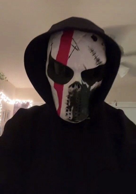 a person wearing a mask with red and white stripes on it's face, standing in a living room