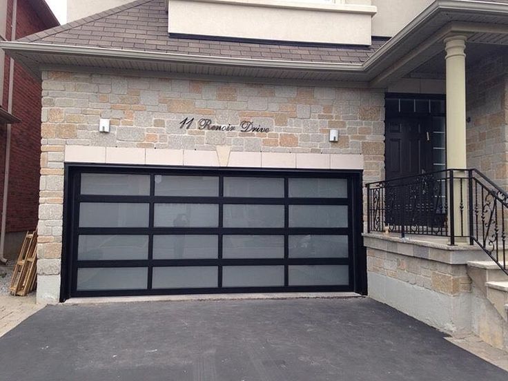 a black garage door on the side of a brick building with stairs leading up to it