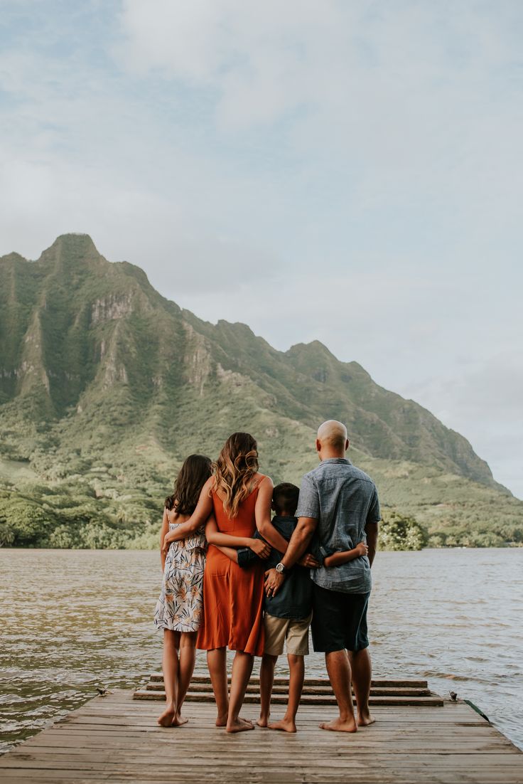 four people standing on a dock with mountains in the background