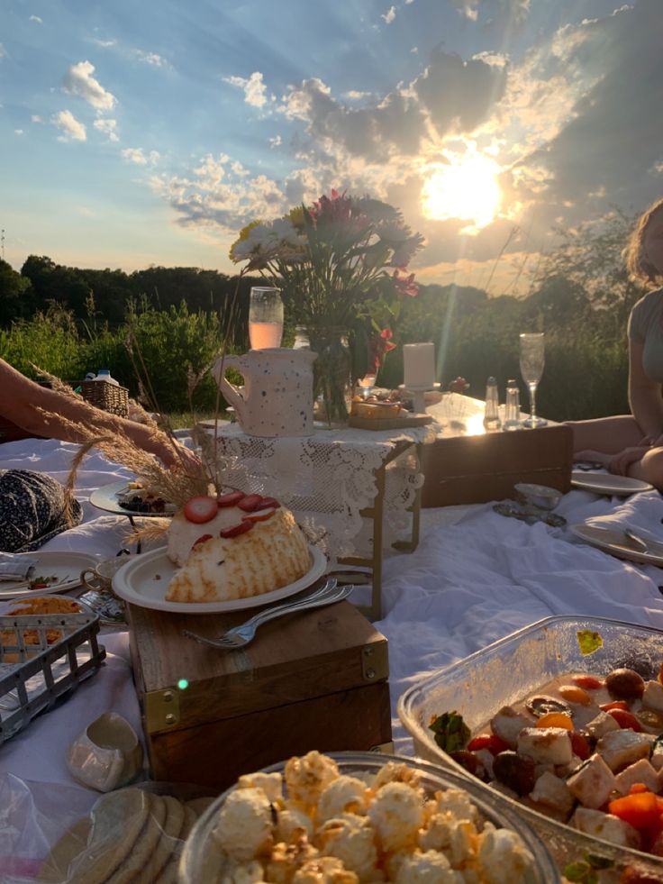 people sitting at a table with food and drinks on it, in front of the sun