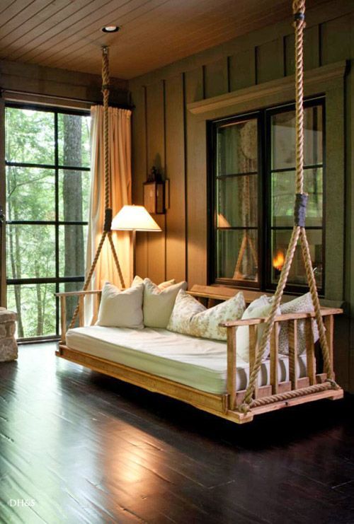 a swing bed in the middle of a room with large windows and wooden flooring