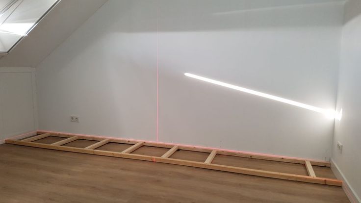 an empty room with wooden flooring and white walls in the corner is lit by pink light