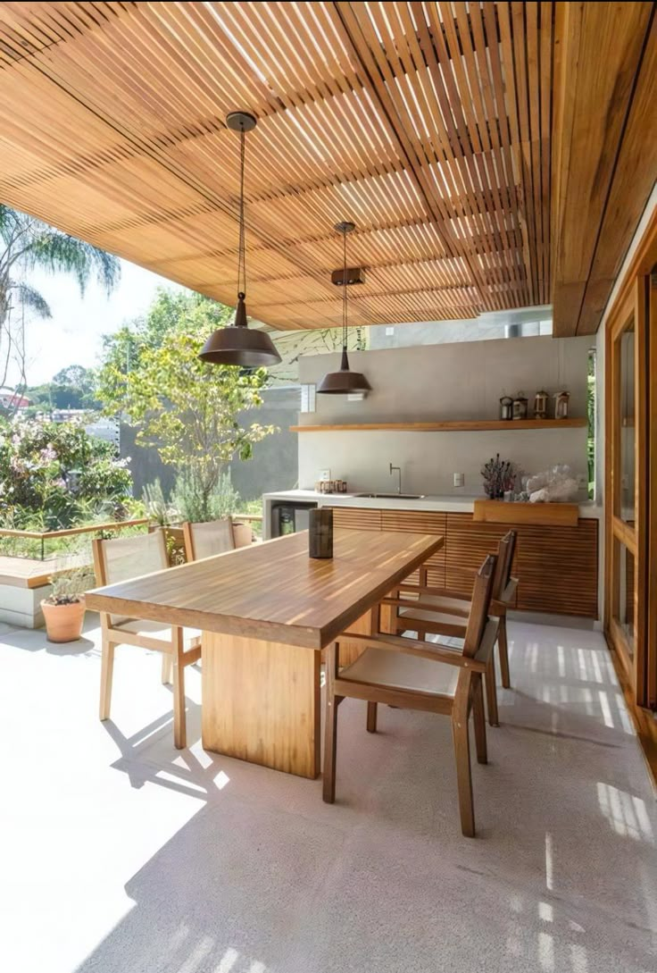 an outdoor kitchen and dining area with wood ceilinging on the outside side of the house