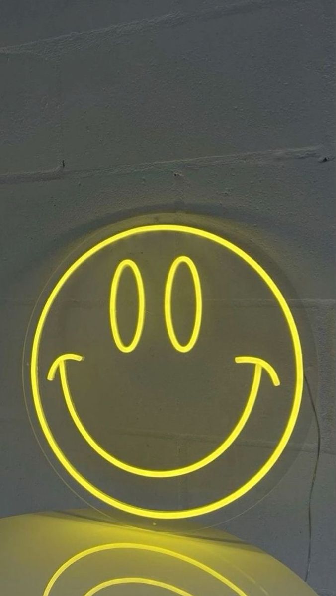 a yellow smiley face on the side of a wall with two circular lights in front of it