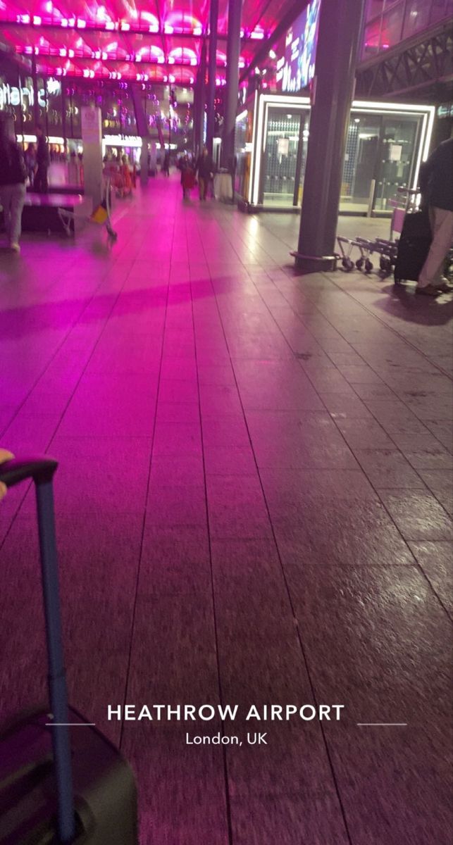 a luggage bag sitting on top of a hard wood floor next to a pink light