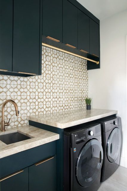 a washer and dryer in a small room with cabinets on either side of the sink