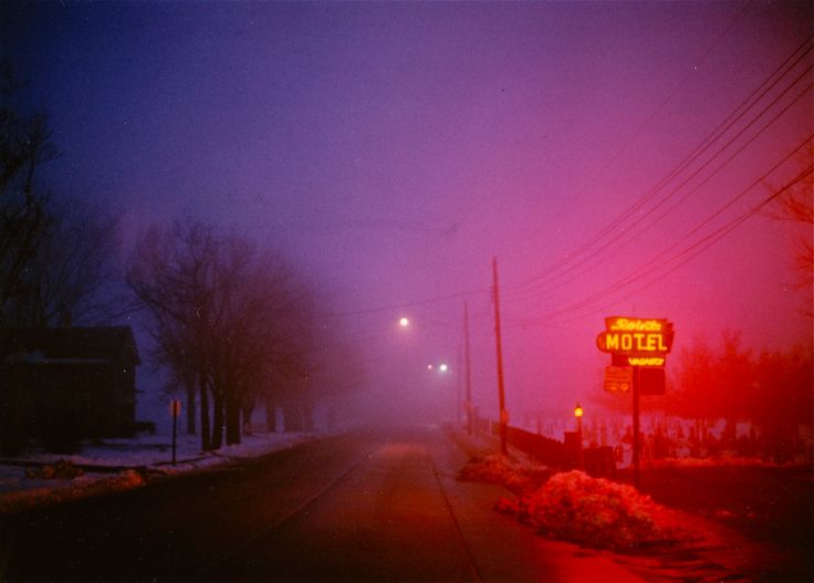 a foggy street with a motel sign in the distance