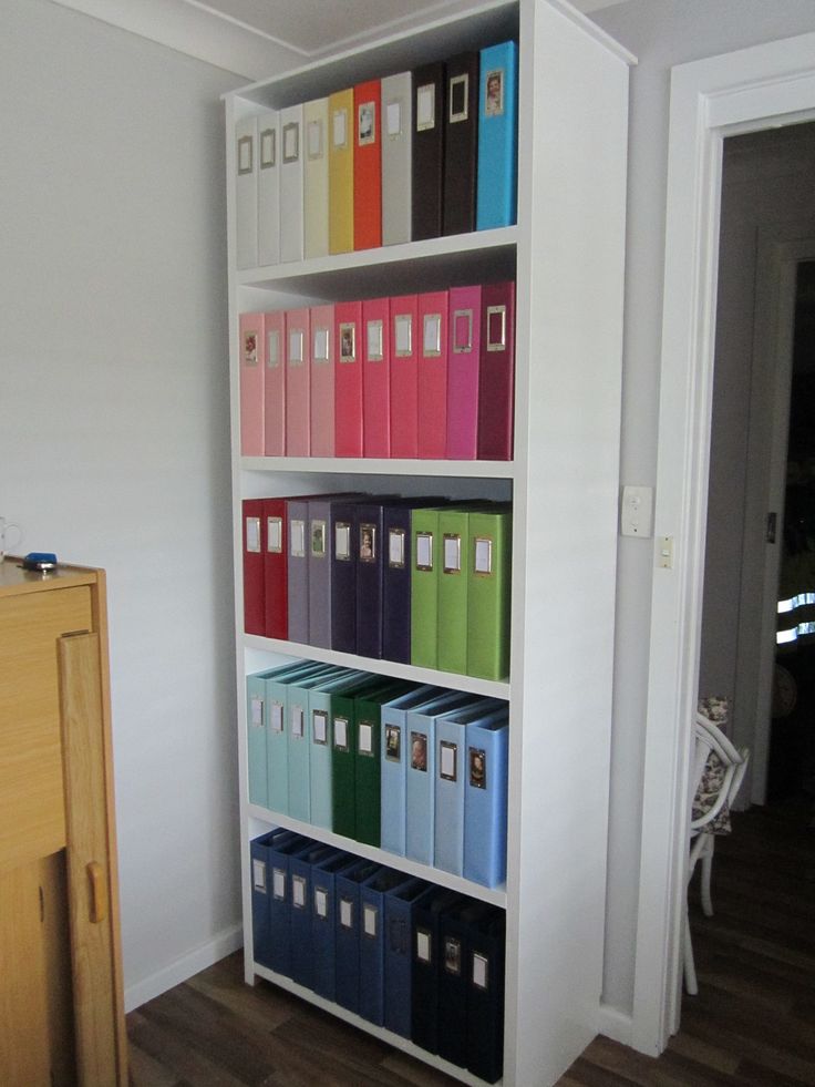 a white book shelf filled with lots of colorful binders and folders on top of it