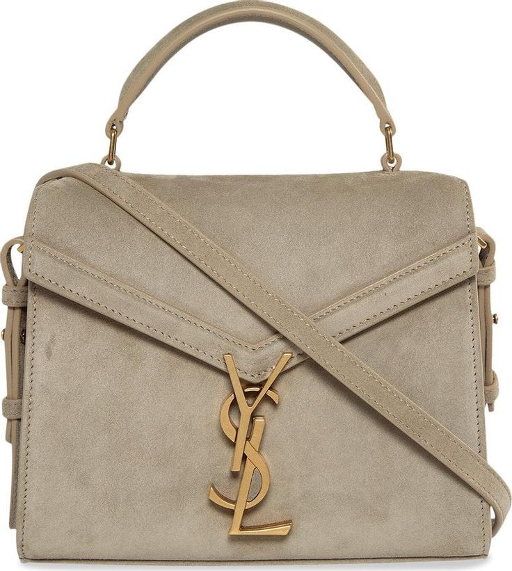 The YSL Mini Cassandra Top Handle Bag epitomizes sophistication and luxury with its exquisite craftsmanship and timeless design. Crafted in Italy from sumptuous suede, complemented by leather lining and antique gold-tone hardware, this bag exudes opulence at every turn. Its compact yet functional silhouette features a fold-over flap top closure adorned with a pivoting YSL emblem, adding a touch of iconic elegance. Inside, two spacious compartments and an interior flat pocket offer ample storage, Luxury Designer Flap Bag With Metal Hardware, Luxury Shoulder Bag With Gold-tone Hardware For On-the-go, Luxury Shoulder Bag With Suede Lining For On-the-go, Luxury Metallic Shoulder Bag With Gold-tone Hardware, Luxury Designer Flap Bag With Leather Lining, Luxury Timeless Top Handle Bag, Luxury Gold Leather Flap Bag, Luxury Elegant Flap Bag For Women, Luxury Timeless Shoulder Bag With Gold-tone Hardware