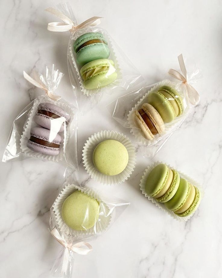 four different types of macaroons wrapped in cellophane on a marble surface