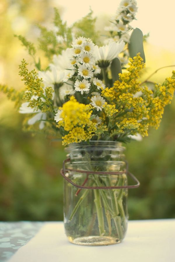 a jar filled with flowers sitting on top of a table next to a sign that says wednesday have a great day