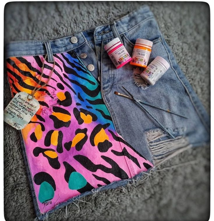 a pair of jean shorts with paint and nail polish on them next to some other items