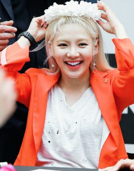 a woman is smiling and holding her hair in front of her head while sitting at a table