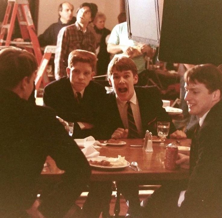 a group of young men sitting around a wooden table