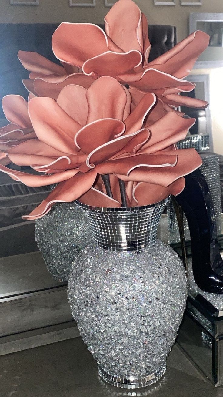 a vase filled with flowers sitting on top of a table next to a mirror wall