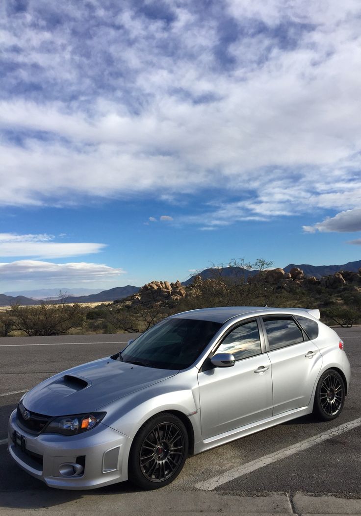 a silver car parked in a parking lot with mountains in the background