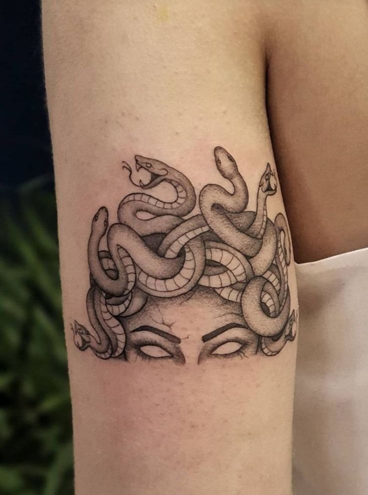 a woman's arm with a tattoo on it that looks like a snake wrapped around her head