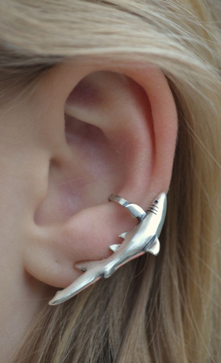 a close up of a person's ear with two small silver dolphins on it