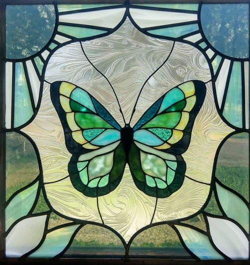 a close up of a stained glass window with a butterfly on it's wings