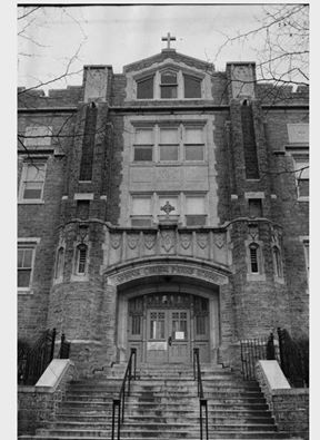 black and white photograph of an old building with stairs leading up to the front door