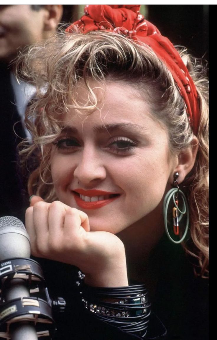 a woman with curly hair wearing a red headband and holding a microphone in her hand