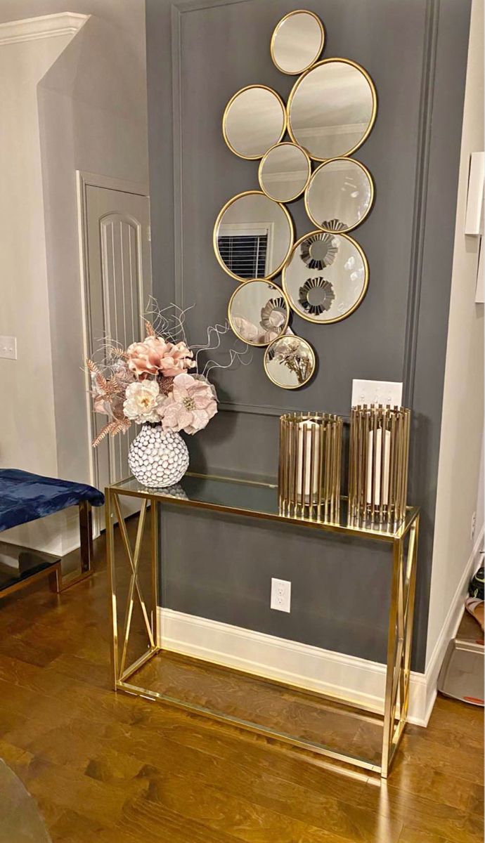 a console table with vases and plates on it in front of a mirror wall