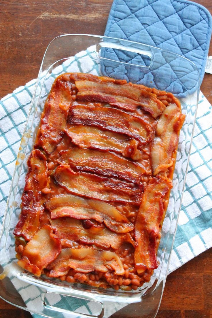 a glass dish filled with bacon sitting on top of a blue and white towel