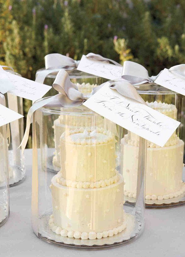 several small cakes in glass containers with ribbons on them