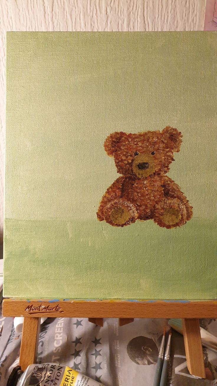 a brown teddy bear sitting on top of a wooden easel