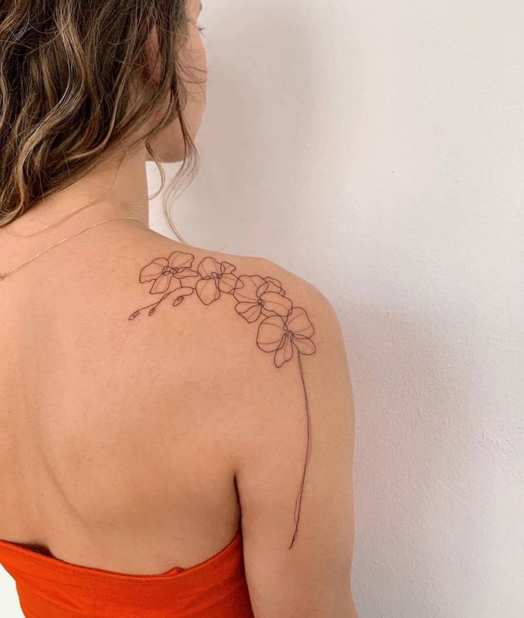 the back of a woman's shoulder with a flower tattoo on her left arm