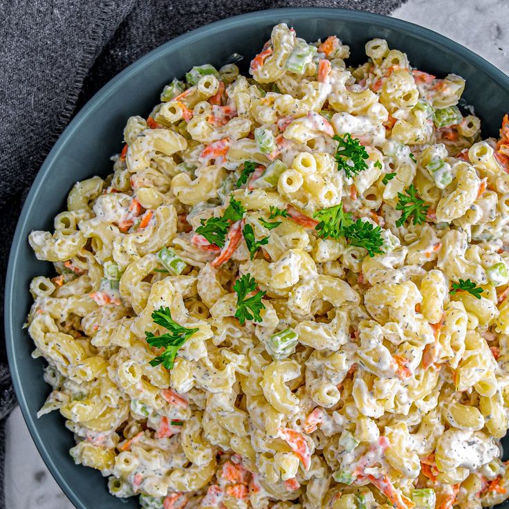 a bowl filled with macaroni salad and garnished with fresh parsley