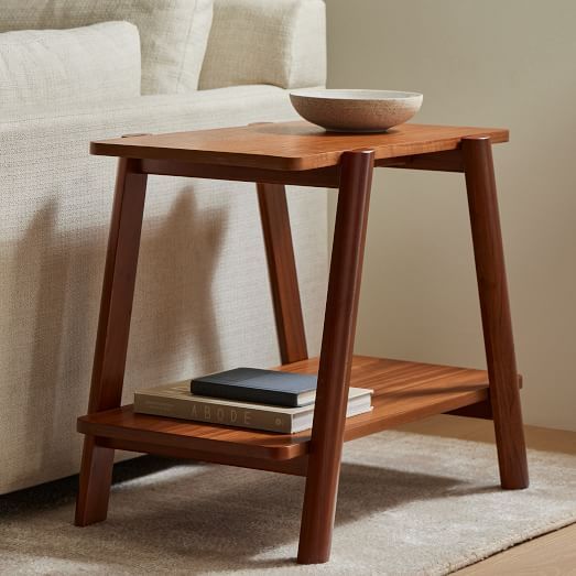 a wooden table with a bowl on top of it next to a white couch in a living room